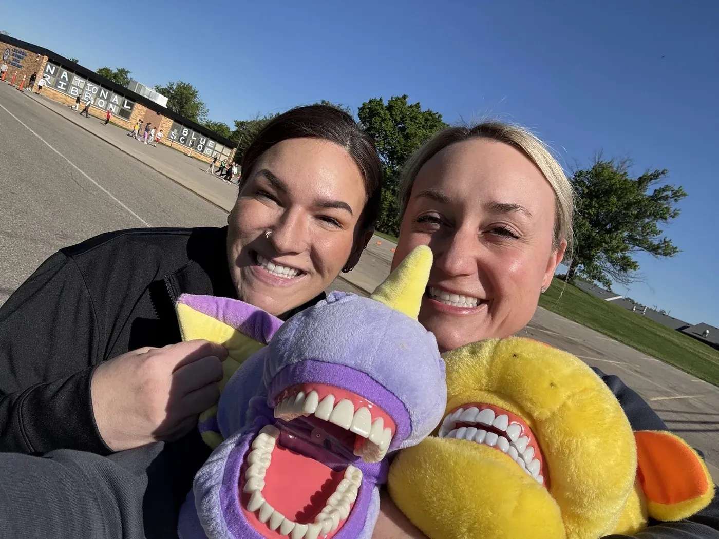 Dr. Oberlander and a colleague at an outdoor event, holding tooth puppets