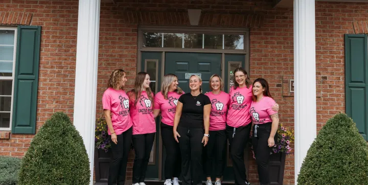 The Cactus Pear Dental team standing together and laughing on the front step of the practice