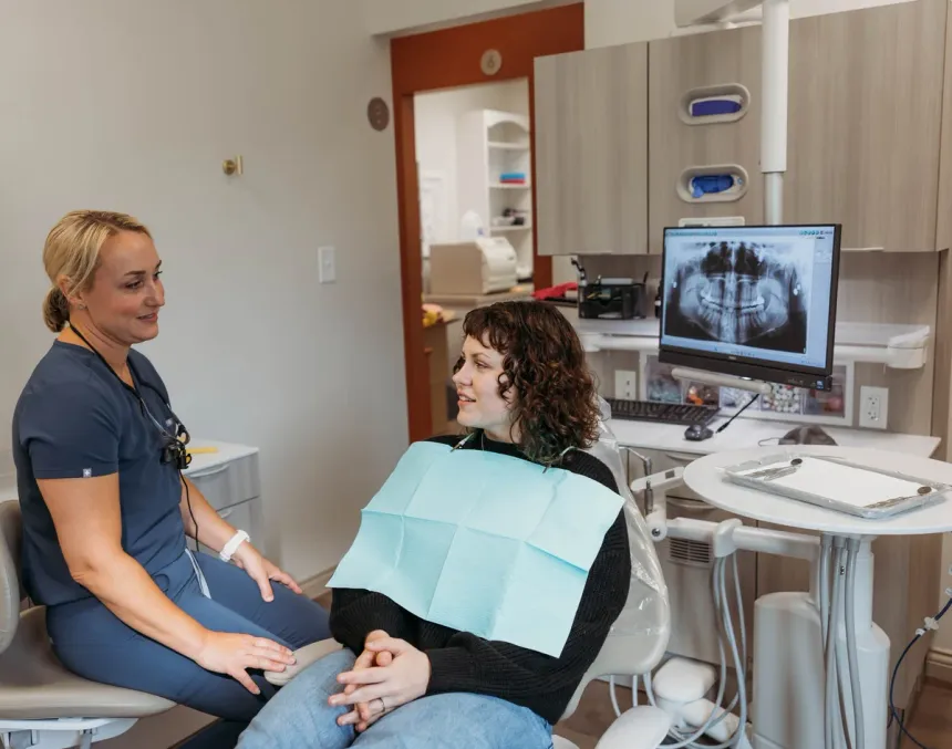 Dr. Kim Oberlander turned toward a patient in the chair, a panoramic X-ray displayed on the monitor beside them
