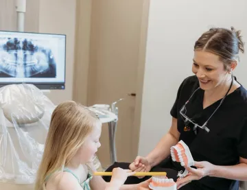 A team member showing a young patient how to brush